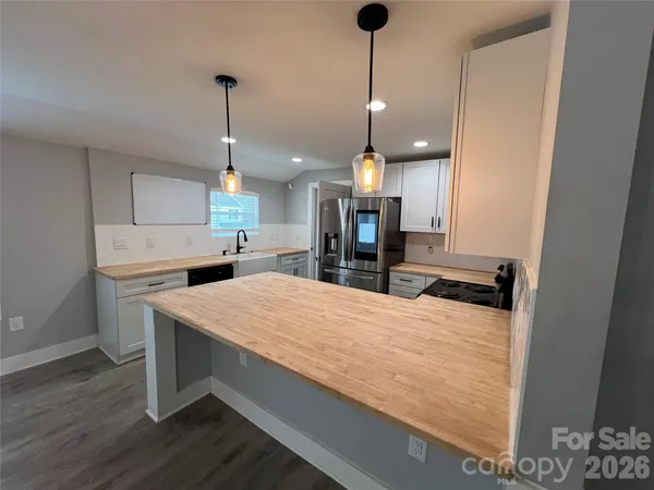 a large kitchen with kitchen island a stove a counter space a sink and a fireplace