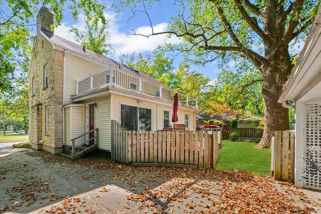 a view of a small white house with a small yard and large trees