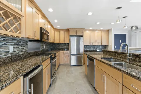 a kitchen with stainless steel appliances granite countertop a sink a stove and a microwave
