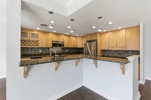 a kitchen with stainless steel appliances granite countertop a sink refrigerator and cabinets