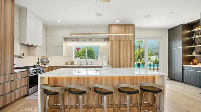 a living room with stainless steel appliances furniture a flat screen tv and a kitchen view