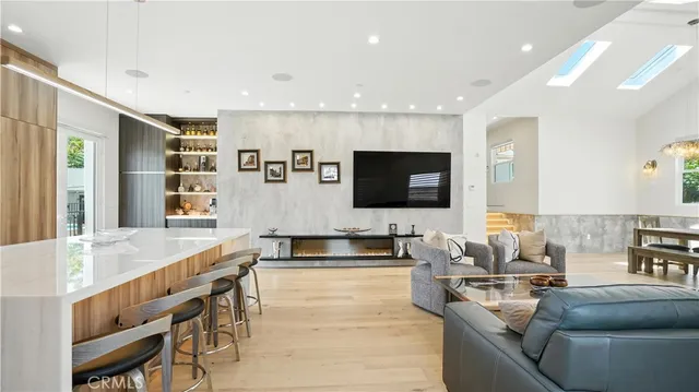 a living room with stainless steel appliances kitchen island granite countertop a sink and a flat screen tv