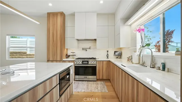 a kitchen with kitchen island granite countertop a sink cabinets and stainless steel appliances