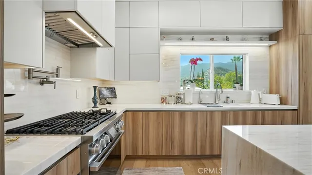a living room with stainless steel appliances furniture a flat screen tv and a kitchen view