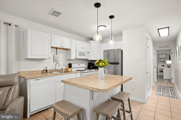 a kitchen with a sink a stove a refrigerator and white cabinets