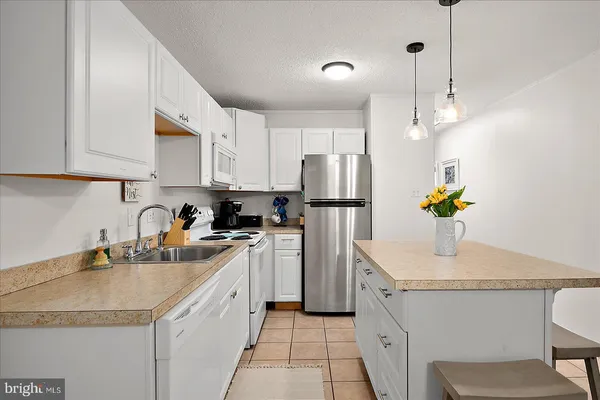 a kitchen with stainless steel appliances granite countertop a sink a stove a refrigerator a center island a stove and cabinets