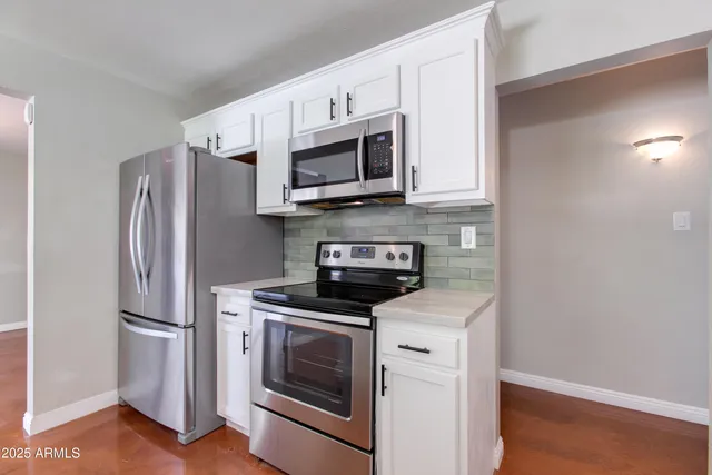 a kitchen with stainless steel appliances white cabinets white stove a microwave and a refrigerator