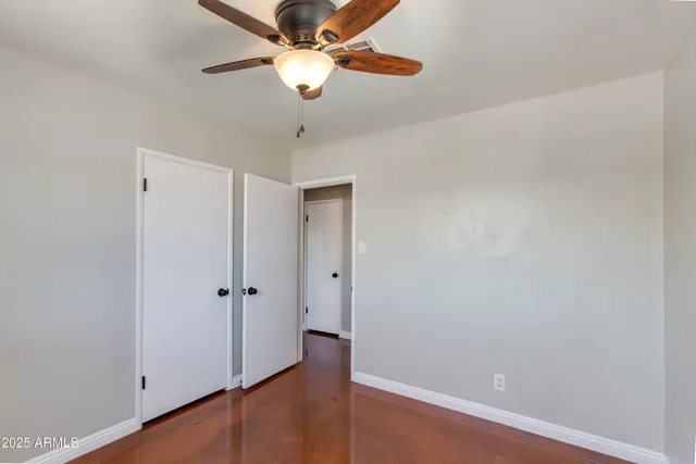 an empty room with wooden floor fan and a window