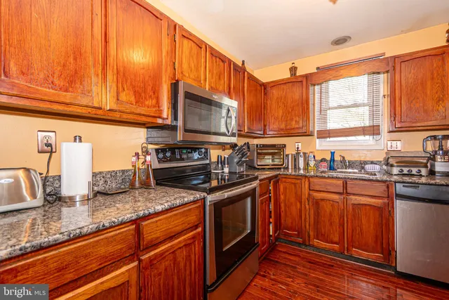 a kitchen with stainless steel appliances granite countertop a refrigerator a sink and wooden cabinets