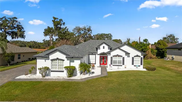 a view of a house with a big yard and large trees