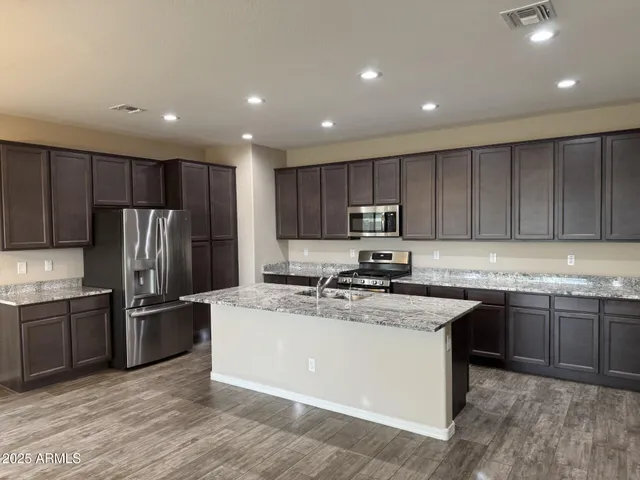 a kitchen with kitchen island granite countertop stainless steel appliances and wooden cabinets