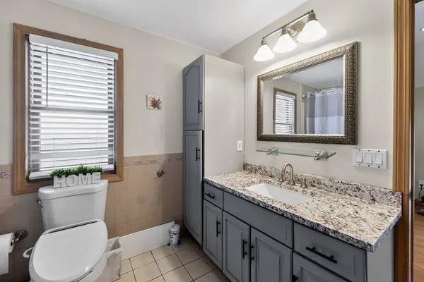 a bathroom with a granite countertop sink toilet and mirror