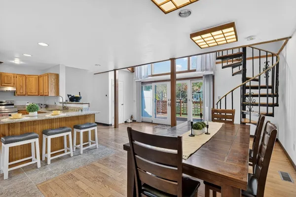 a living room with stainless steel appliances furniture a rug kitchen view and a table