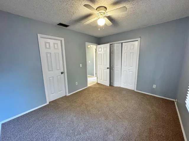 a view of an empty room and chandelier fan