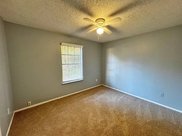 an empty room with windows and chandelier fan