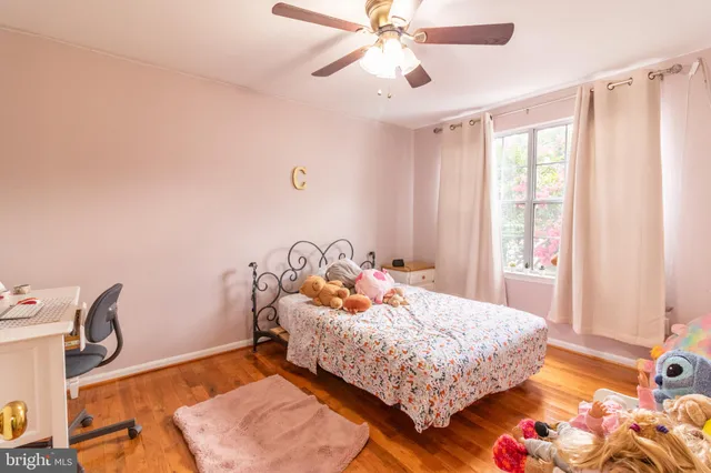 a bedroom with a bed and a dresser with wooden floor