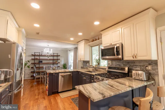 a kitchen with stainless steel appliances a sink a stove a refrigerator cabinets and a dining table