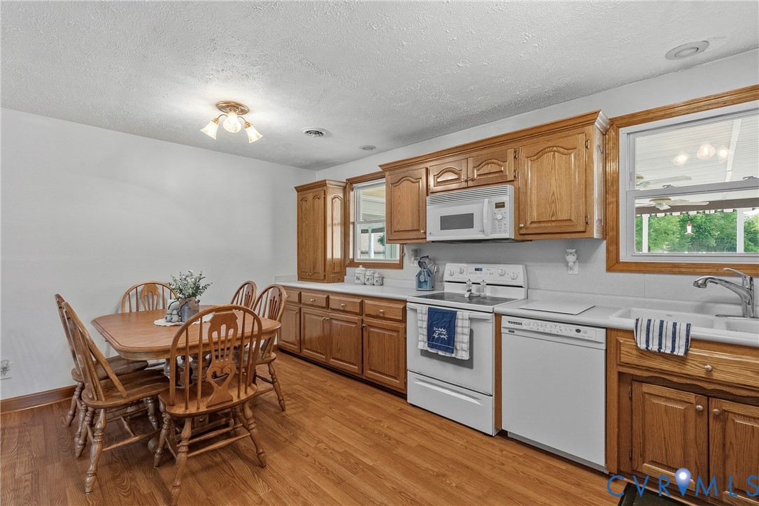 18024 Sandy Ford Road Petersburg, VA 23803 - Photo 18 of 66 a kitchen with stainless steel appliances granite countertop a stove top oven a sink dishwasher a dining table and chairs with wooden floor