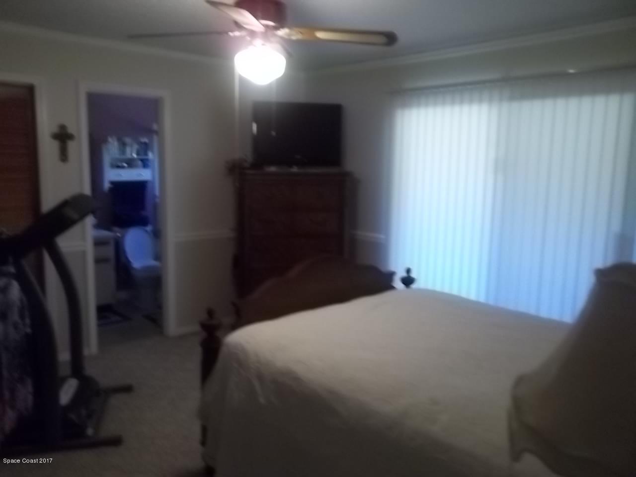 1081 Sapulpa Road Southwest Palm Bay, FL 32908 - Photo 5 of 10 a bedroom with a bed and a chandelier