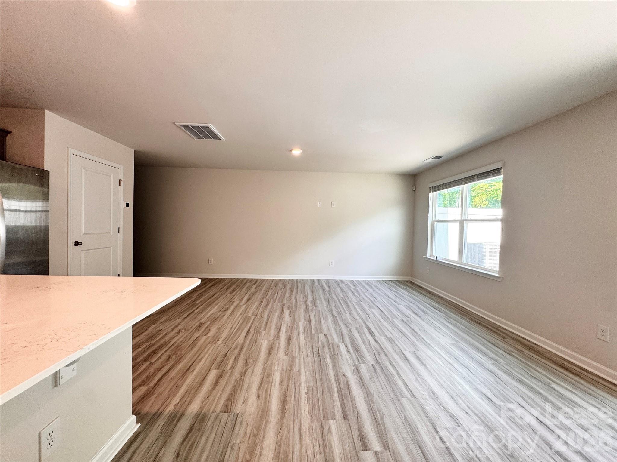 6131 Faron Way Charlotte, NC 28262 - Photo 5 of 18 a view of an empty room with wooden floor and a window