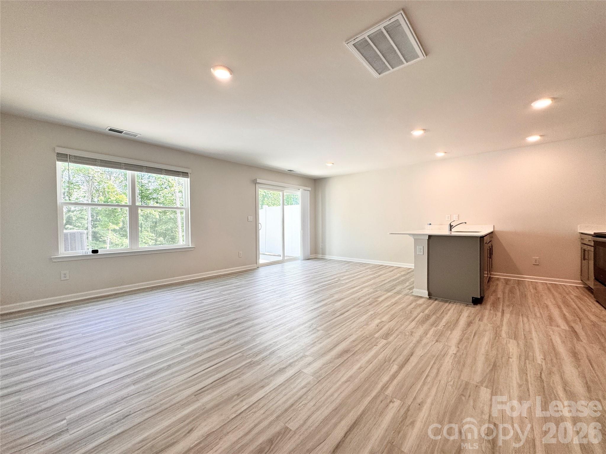 6131 Faron Way Charlotte, NC 28262 - Photo 6 of 18 an empty room with wooden floor and windows