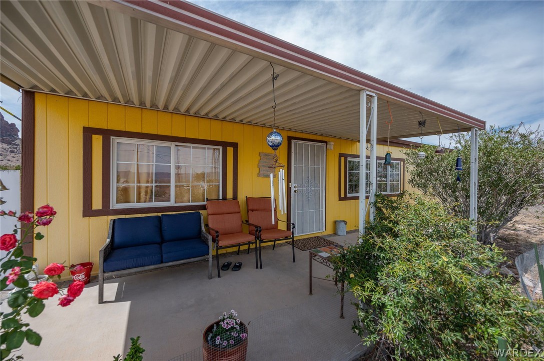 2465 Egar Road Golden Valley, AZ 86413 - Photo 2 of 98 The property features a covered patio with a yellow exterior, white windows with brown trim, and a decorative white security screen door