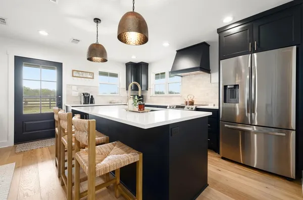 a kitchen with stainless steel appliances kitchen island granite countertop a sink a refrigerator and a stove