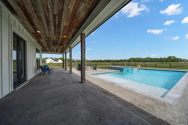 a view of swimming pool with seating space and wooden fence