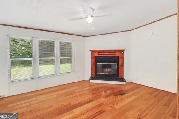 an empty room with wooden floor fireplace and windows