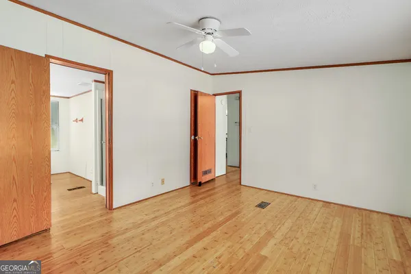a view of empty room with wooden floor and ceiling fan