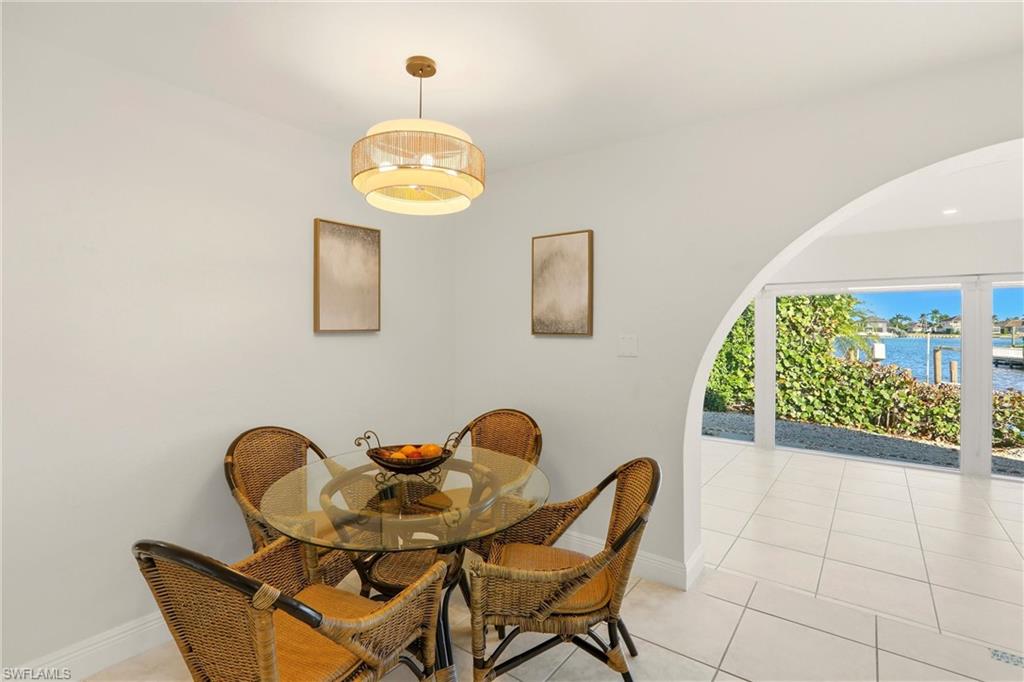 339 Landmark Street Marco Island, FL 34145 - Photo 8 of 50 Dining room featuring light tile patterned floors, a water view, and arched walkways