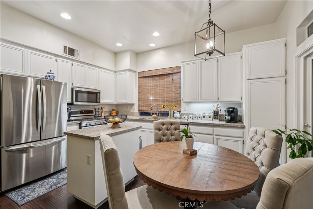 988 Cimarron Place Corona, CA 92879 - Photo 8 of 23 a kitchen with stainless steel appliances granite countertop a sink a stove a refrigerator cabinets and chairs