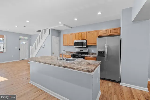 a kitchen with stainless steel appliances granite countertop a refrigerator a sink a stove a microwave and island with wooden floor