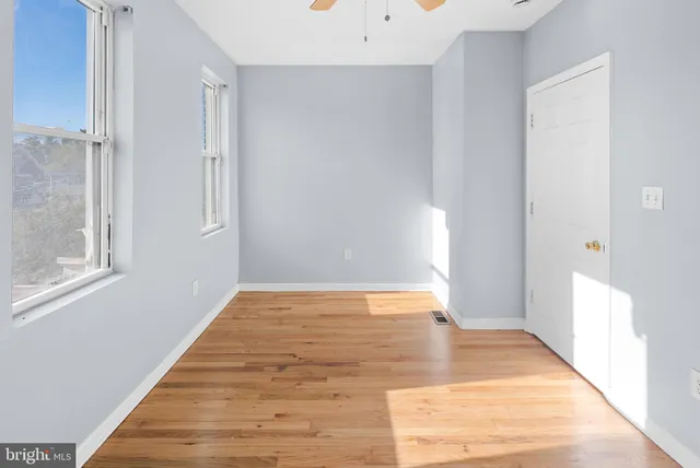 a view of an empty room with wooden floor and a window