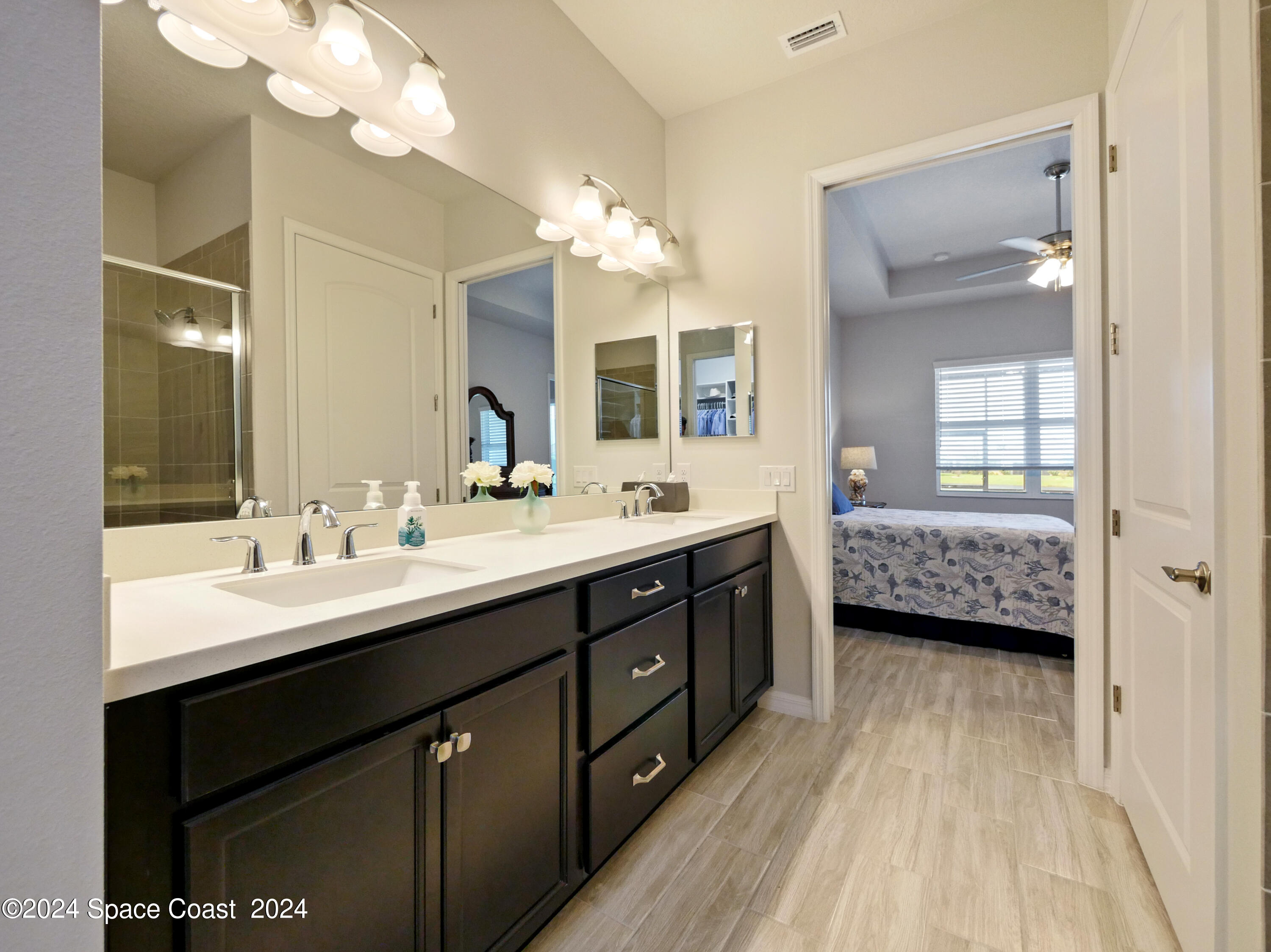 3149 Avalonia Drive Melbourne, FL 32940 - Photo 26 of 31 a en suite bathroom with a double vanity sink a mirror and a shower