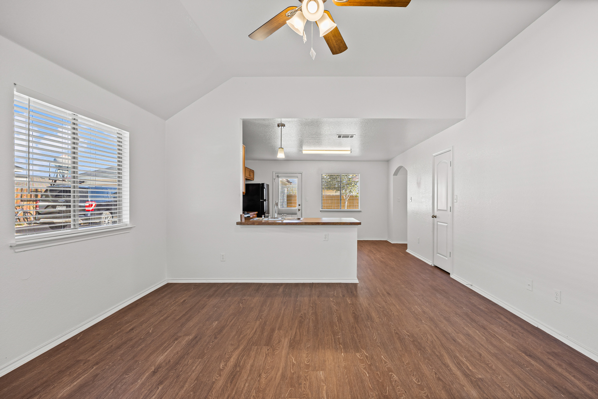 4503 Halliday Avenue Austin, TX 78725 - Photo 7 of 21 Unfurnished living room with dark wood-style flooring, arched walkways, a ceiling fan, and lofted ceiling