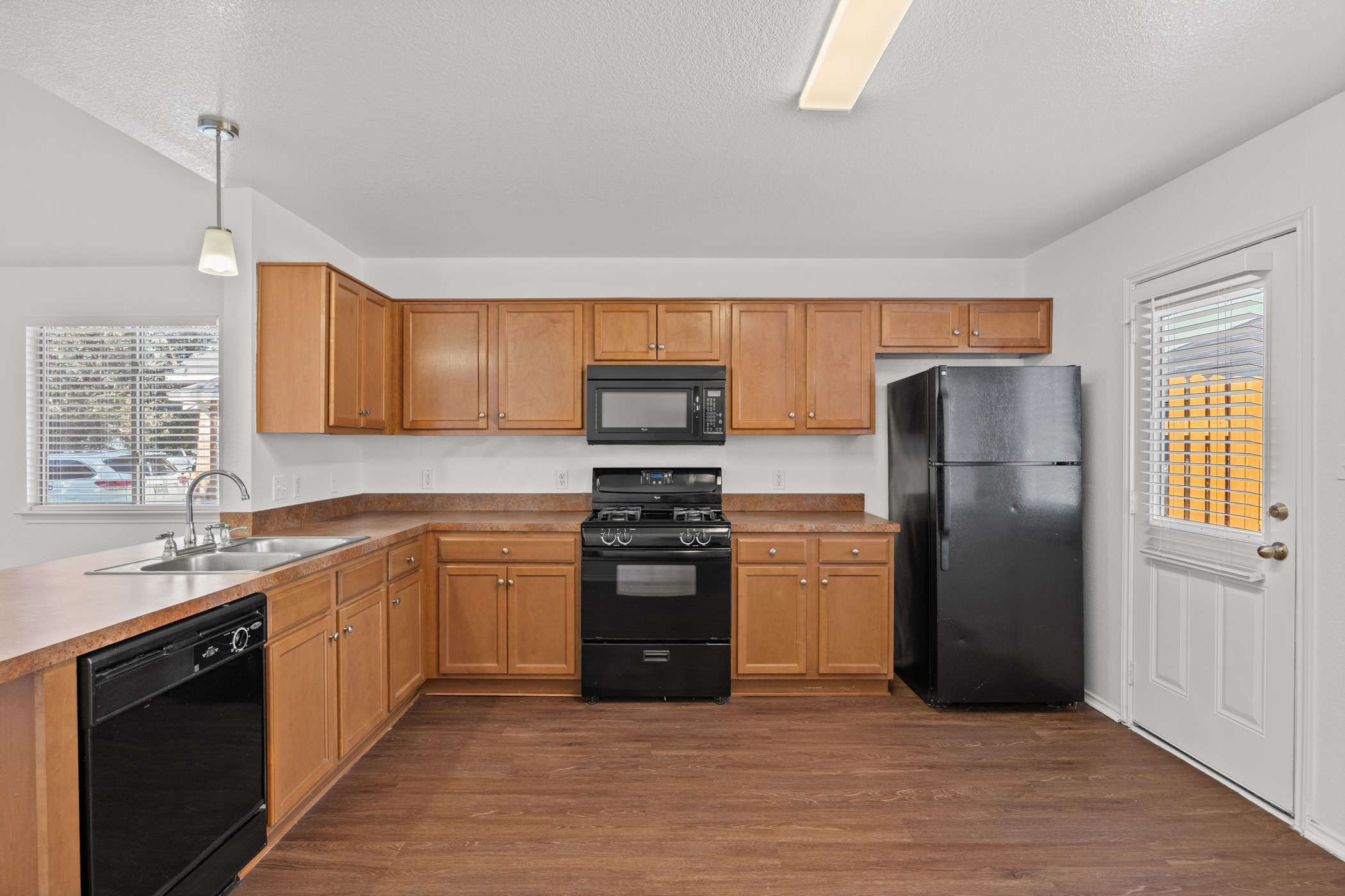 4503 Halliday Avenue Austin, TX 78725 - Photo 10 of 21 Kitchen with black appliances, dark wood-style floors, a textured ceiling, pendant lighting, and light countertops