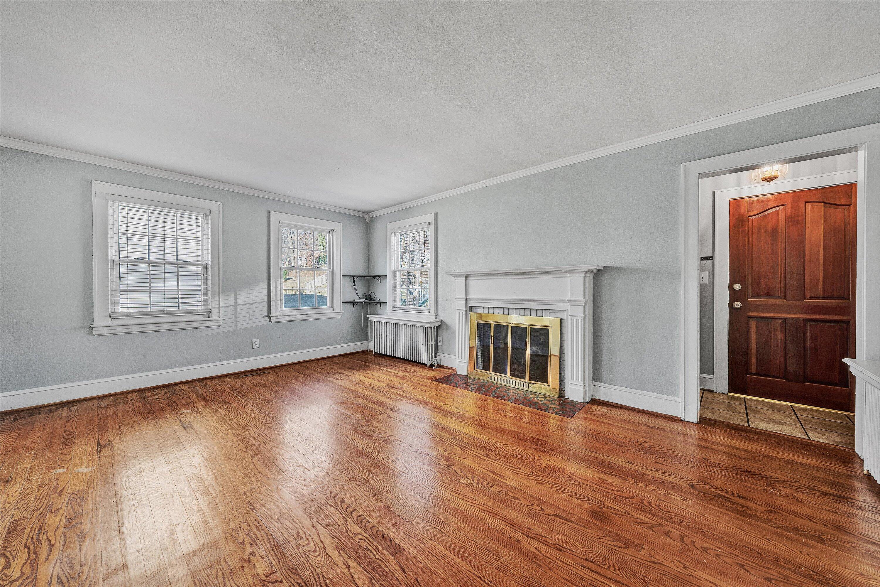 810 Windsor Avenue Southwest Roanoke, VA 24015 - Photo 3 of 21 an empty room with wooden floor fireplace and windows
