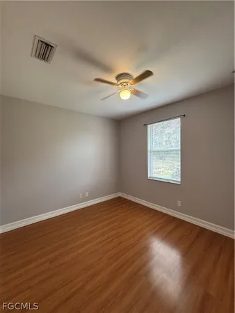 an empty room with wooden floor and window