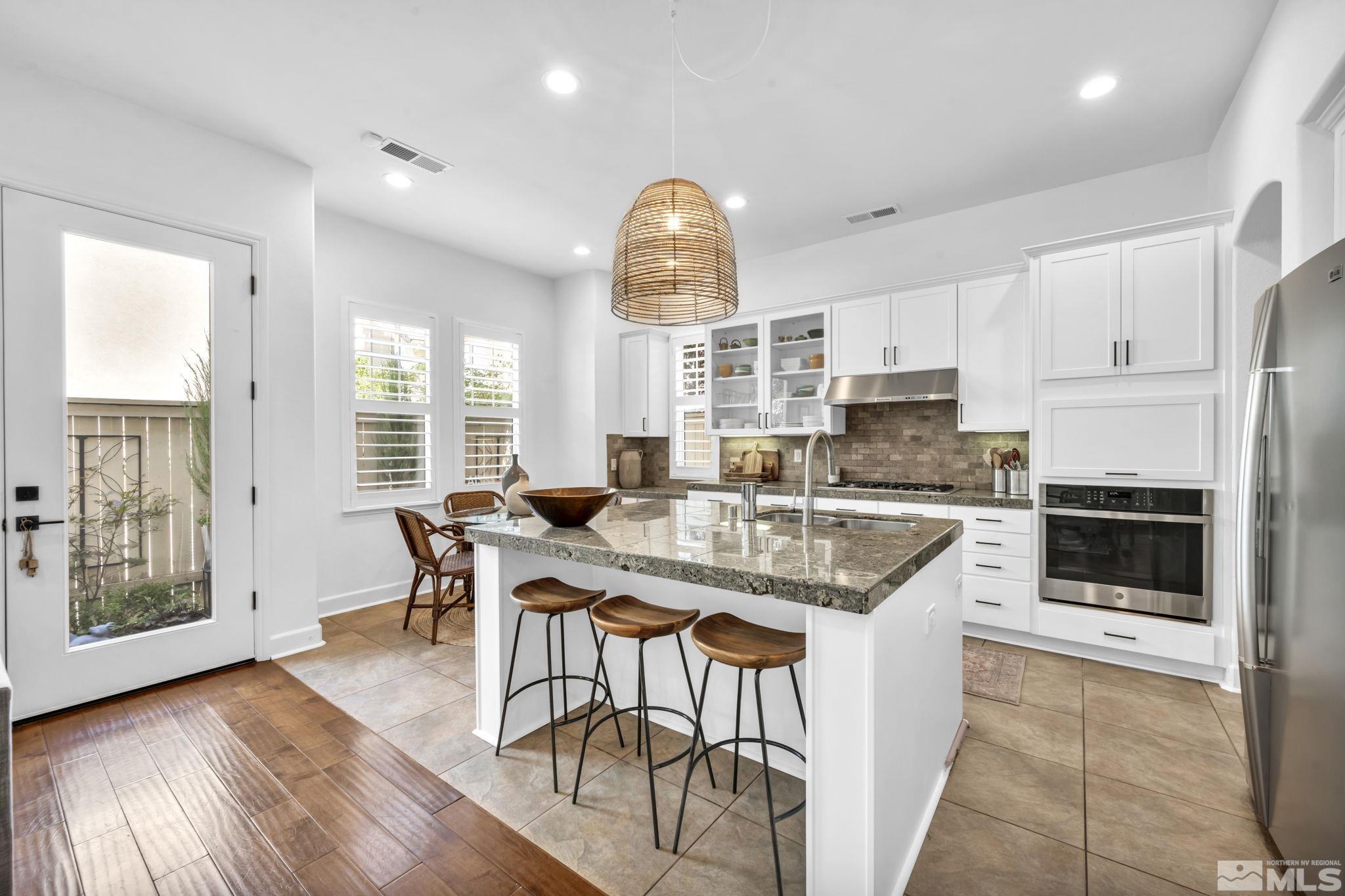 7665 Stone Bluff Way Reno, NV 89523 - Photo 11 of 40 a kitchen with stainless steel appliances granite countertop a stove a refrigerator a kitchen island a table and chairs in it