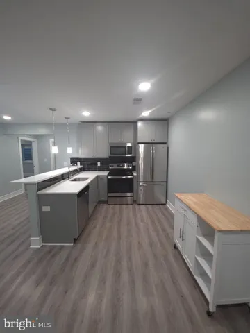 a large kitchen with stainless steel appliances kitchen island a large counter top and a stove top oven