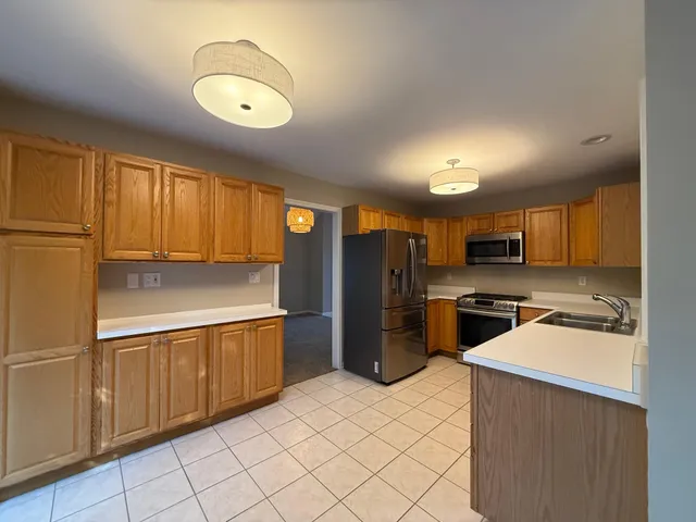 a kitchen with stainless steel appliances granite countertop a refrigerator a stove top oven and sink