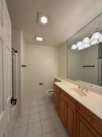 a spacious bathroom with a granite countertop sink a toilet and a mirror