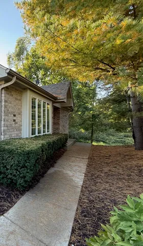 a brick house next to a yard with large trees