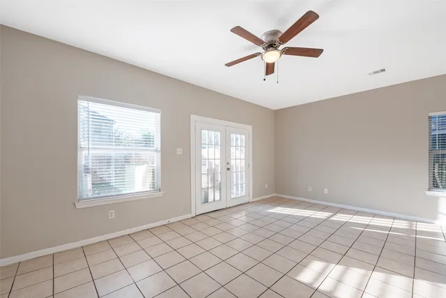 a view of an empty room with window and chandelier fan