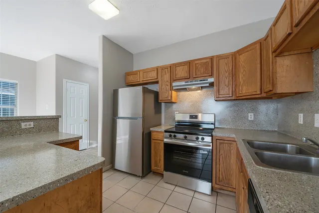 a kitchen with granite countertop a sink stove and refrigerator