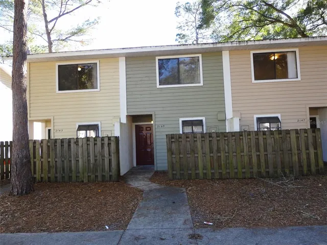 a view of a house with a small yard and wooden fence