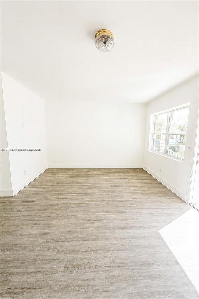 5825 Southwest 9th Terrace, Unit 2 West Miami, FL 33144 - Photo 4 of 11 a view of an empty room with wooden floor and a window