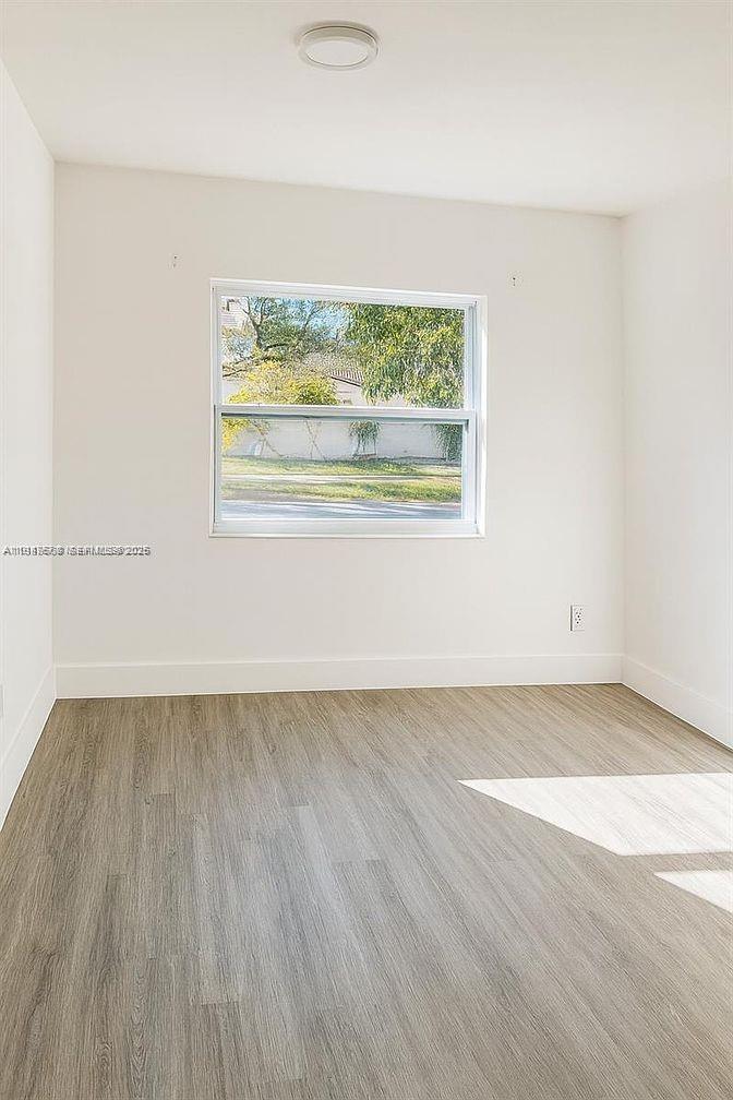 5825 Southwest 9th Terrace, Unit 2 West Miami, FL 33144 - Photo 9 of 11 an empty room with wooden floor and window