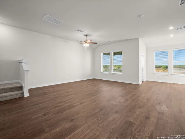 an empty room with wooden floor chandelier and windows